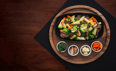 Top view of stir fried mixed vegetables in plate on wooden table background. Healthy Food