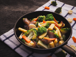 Stir fried mixed vegetables in pan on wooden table background. Healthy Food