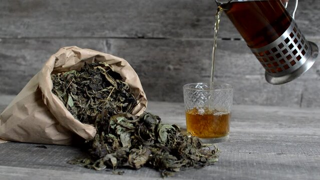 Green tea pouring into a glass on a wooden background. High quality FullHD footage
