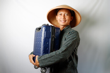 Indonesian farmer wearing Lurik and Caping smiling happy while carrying travelling suitcase