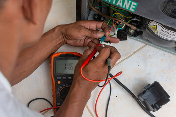 A technician repairs an old personal refrigerator. Checking the voltage of a relay and thermostat...
