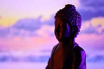 Buddha Purnima and Vesak day concept, Buddha statue with low key light against beautiful and colorful background close up. Meditation