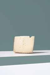 Trozo de queso de oveja curado. Cuña de queso manchego sobre fondo verde