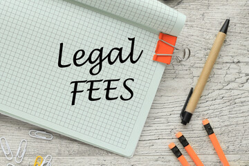 the text LEGAL FEES . Business orange pencils and pen. text on the corner of the notebook