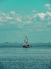 Fototapeta premium Vertical sho too a sailboat in the sea with the blue sky in the background