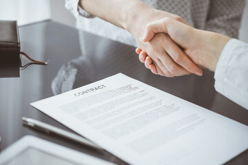 Business people signing contract papers while sitting at the glass table in office, closeup. Partners or lawyers working together at meeting. Teamwork, partnership, success concept