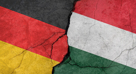 Germany and Hungary flags, concrete wall texture with cracks, orange background, military conflict concept