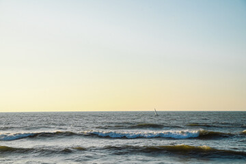 A sailboat sails against a sunset in the Mediterranean Sea