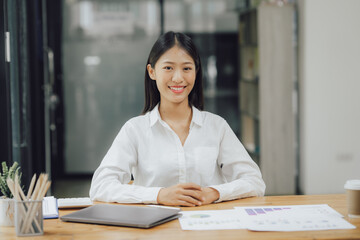 Asian businesswoman working on laptop computer in office with documents on desk woman looking at financial statistics data analysis chart profit growth business idea vertical image