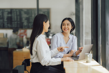 Beautiful young smiling Asian businesswoman working on laptop and drinking coffee, Asia businesswoman working document finance and calculator in her office.