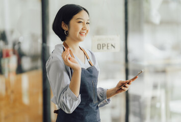 Startup successful small business owner sme beauty girl stand with tablet smartphone in coffee shop restaurant. Portrait of asian tan woman barista cafe owner. SME entrepreneur seller business concept