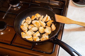 chicken breasts meat only on frying pan and wooden spatula, domestic healthy cuisine in real life situation.