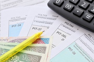 Declaration of the amount of earned income or incurred loss, PIT-36, PIT-36L, PIT-37 and PIT-38 tax forms on accountant table with pen and calculator close up