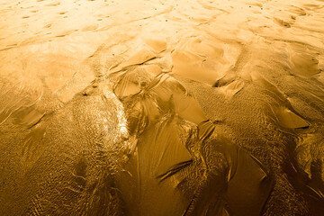 Surface sableuse humide avec rides et chenaux d'écoulement en dégradé de jaune et or et fort contraste de lumière pour arrière-plan - obrazy, fototapety, plakaty