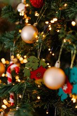 A New Year's toy in the shape of a green wooden dragon hangs on a branch on a Christmas tree. Glowing festive background. Chinese horoscope 2024. Zodiac sign