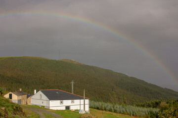 a rainbow from a house in the mountains