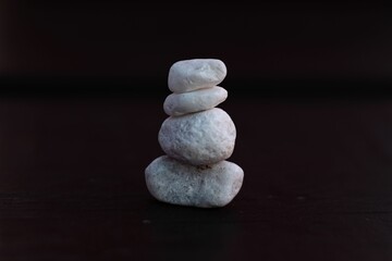 Fototapeta na wymiar Closeup of a stack of miniature balancing rocks for zen against the black background