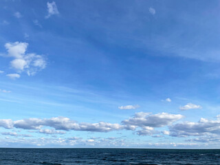 Obraz premium Seascape. Dark turquoise sea with small waves and a bright blue sky with white clouds. The horizon line is visible in the distance. Sunny autumn day.