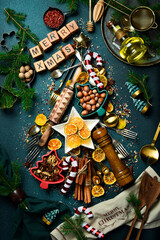 Christmas tree made of vintage kitchen stuff, spices, sweets and utensils. On a dark slate background. Top view.