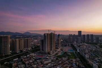 Gorgeous aerial view of a city with skyscrapers under a purple-pink sky at sunset