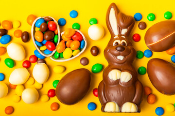 Easter chocolate bunny on a light texture table. Chocolate eggs and other sweets. Easter celebration concept. Easter sweets on the table. Place for text. copy space.
