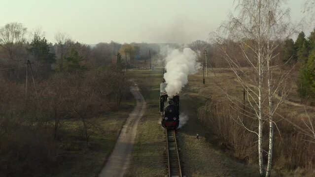 Aerial view of old steam train running on the tracks in the countryside