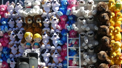 Soft plush toys hanging in a row on the wall outdoors at a carnival in Sydney, Australia.