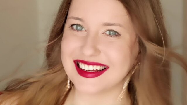 Happy woman smiling with perfect white teeth smile and posing in close-up portrait, female model with long hair wearing golden earrings and red lipstick make-up, jewellery fashion and beauty