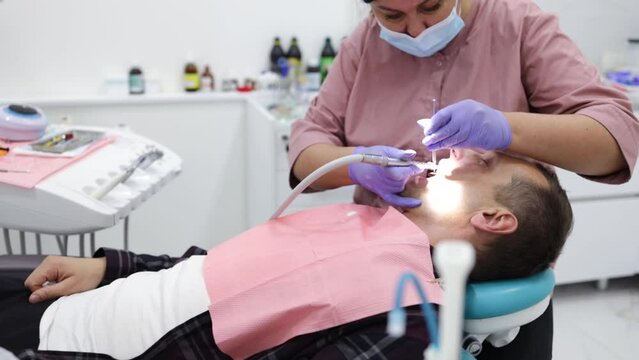 People health and dental care, woman at work as dentist with assistant and visiting young man as client in professional lab of medical clinic. 