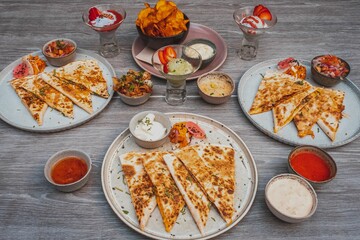 High angle view of slices of Quesadilla and sauces on a table