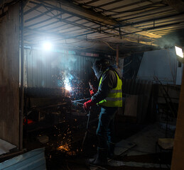 Fototapeta na wymiar Welder working at dark construction site