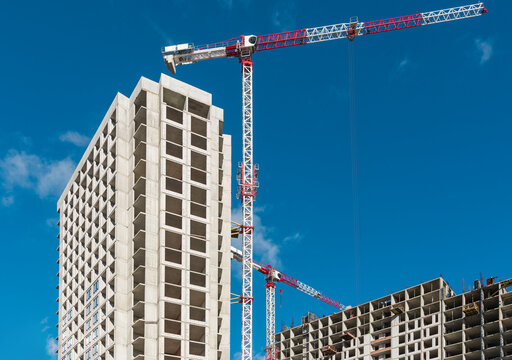 Construction site background, crane and tall building against blue sky