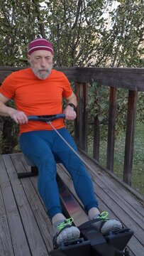senior man is exercising with rowing machine on a backyard deck