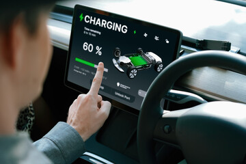 Electric car driver checks battery charging status, range and charging limit on app screen in the car. Smart technology device show EV car recharging data of electric storage in car battery innards. - obrazy, fototapety, plakaty