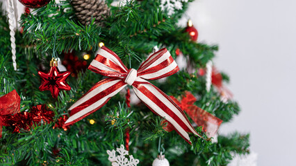 Christmas tree branches are beautifully decorated with a Xmas red and white bow.
