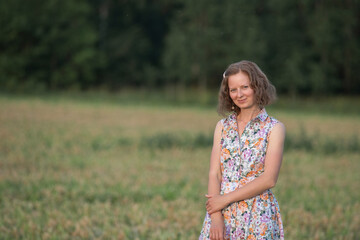 Portrait of a young beautiful girl in a light dress on a summer field.
