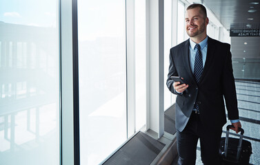 Business man, smartphone and window in airport hallway with smile, thinking and vision on international travel. Entrepreneur, luggage and phone with flight schedule for global immigration in London