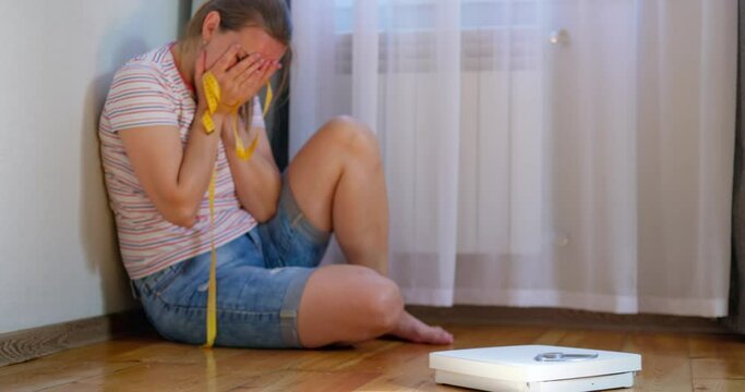 Scales and depressed, frustrated and sad woman crying while sitting on the floor