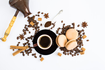 Black coffee in the brown cup, macaron, coffee beans and turk for making coffee on the white background. Copy space. Top view.