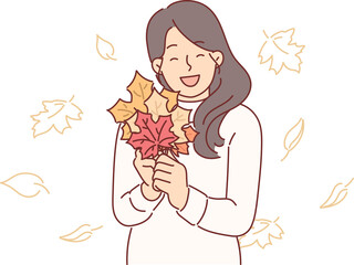 Woman holds autumn foliage of different colors in hands, collecting tree leaves to create herbarium