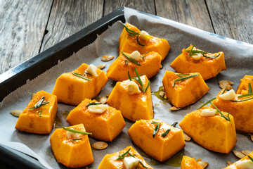 Uncooked pumpkin with rosemary and garlic on wooden table