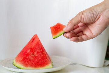 The water melom cut into slices with a womam hand