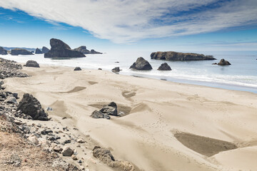 Panoramic view of the Pacific Ocean coastline seascape in Oregon with rock formations scattered offshore and waves.