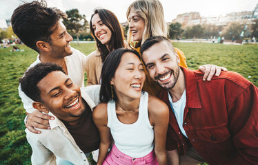 Multiracial young people laughing together outside - Happy friends having fun hanging out on summertime - Friendship concept with guys and girls hangout at the park - obrazy, fototapety, plakaty