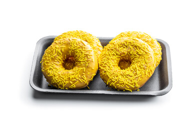 Yellow frosted doughnuts in gray tray isolated on white