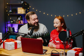 Christmas stream or video blog. Cheerful presenters in holiday clothes raffle off gifts for their...