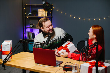 Christmas stream or video blog. Cheerful presenters in holiday clothes raffle off gifts for their...
