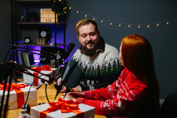 Fototapeta na wymiar A couple of bloggers are doing a Christmas giveaway on their channel. Radio presenters in Christmas sweaters conduct a raffle of gifts among listeners.