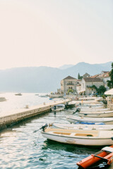 Fototapeta na wymiar Fishing boats are moored in a row between the pier and the shore of Perast. Montenegro