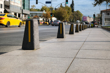 Close-up of a lot of restrictive brown decorative bollards on the road in the city.